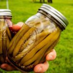 Hands holding two jars of green beans from a Vermont Farmers Market in Waitsfield