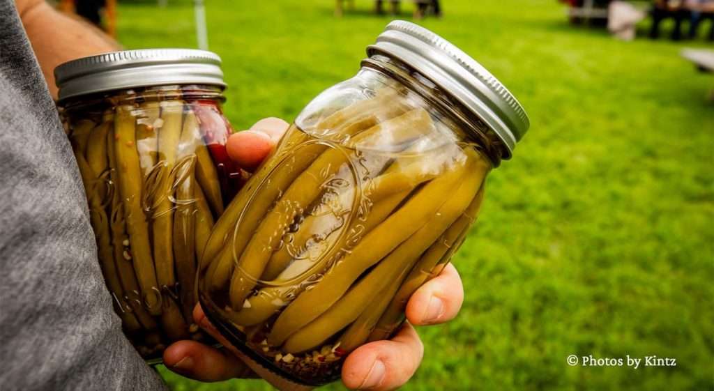 Hands holding two jars of green beans from a Vermont Farmers Market in Waitsfield